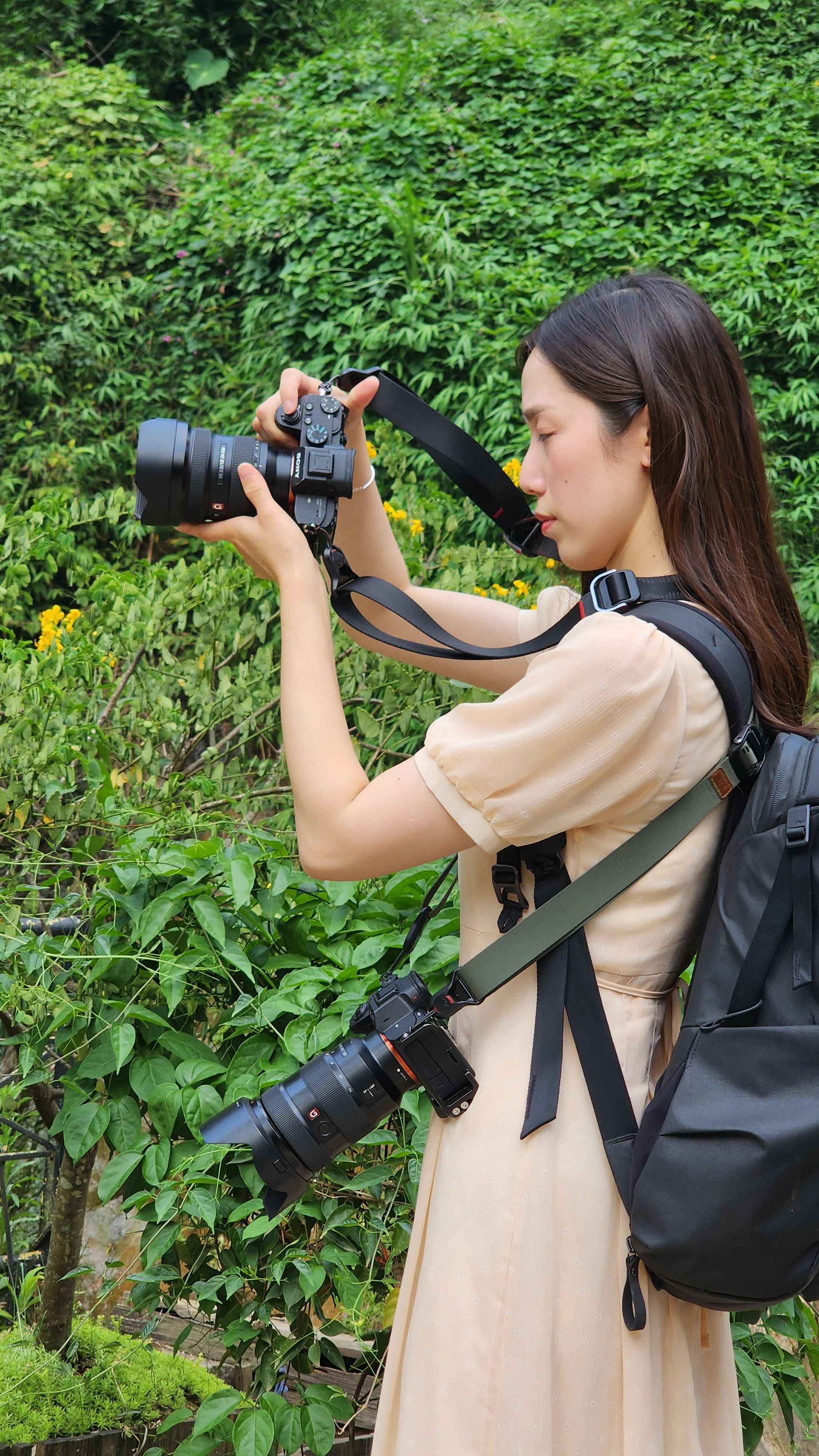 Woman photographer in Sa Pa, Vietnam, documenting lush greenery with professional camera gear.