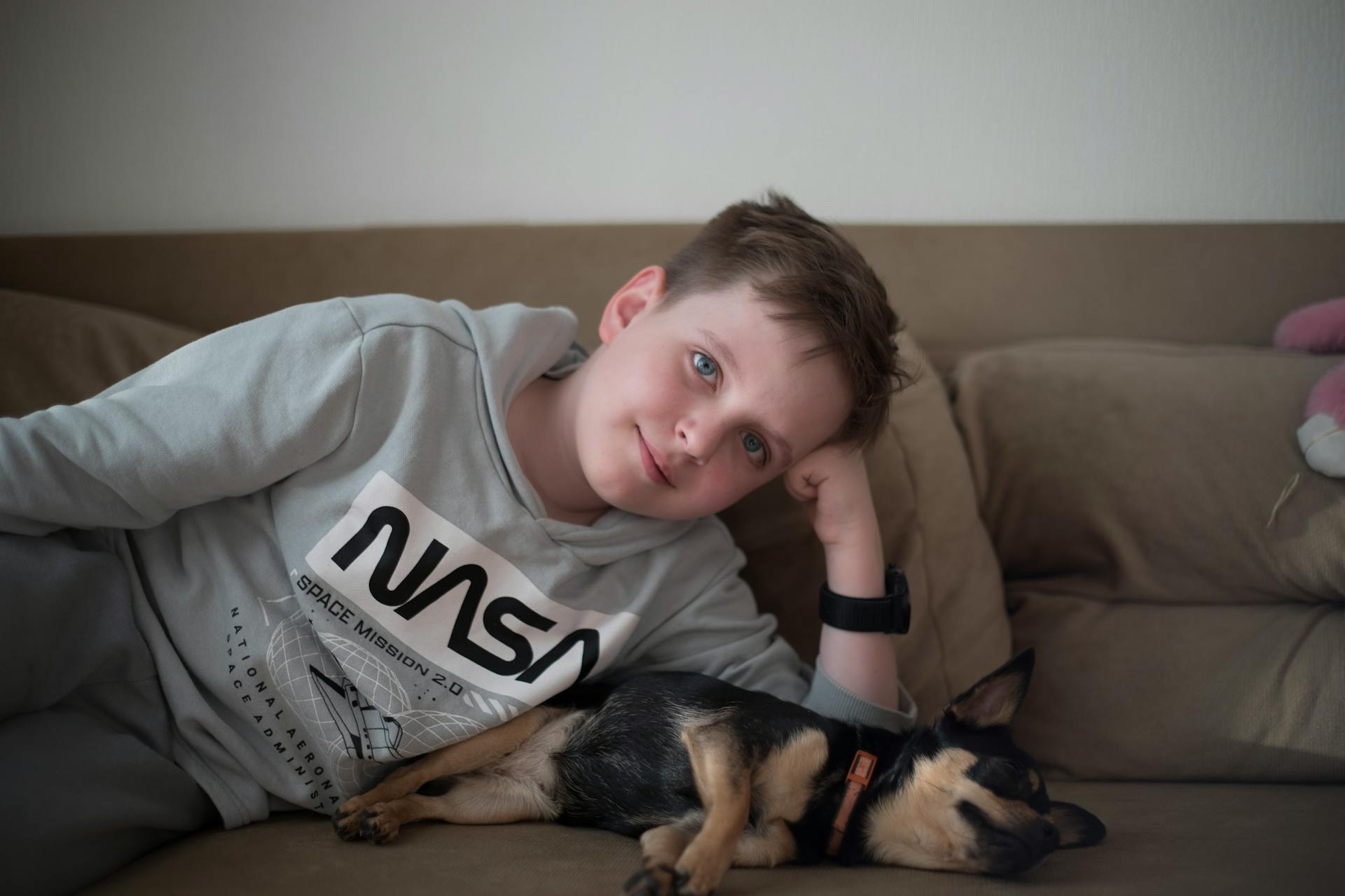 Boy Lying Down on Couch with Sleeping Puppy