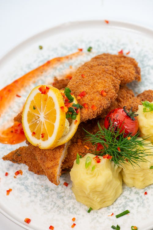 Closeup of a Fish in Batter with Lemon Slices, and Mashed Potatoes