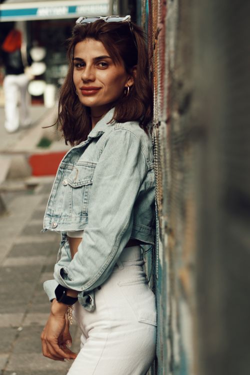 Free Woman in denim jacket posing against graffiti wall in urban environment. Stock Photo