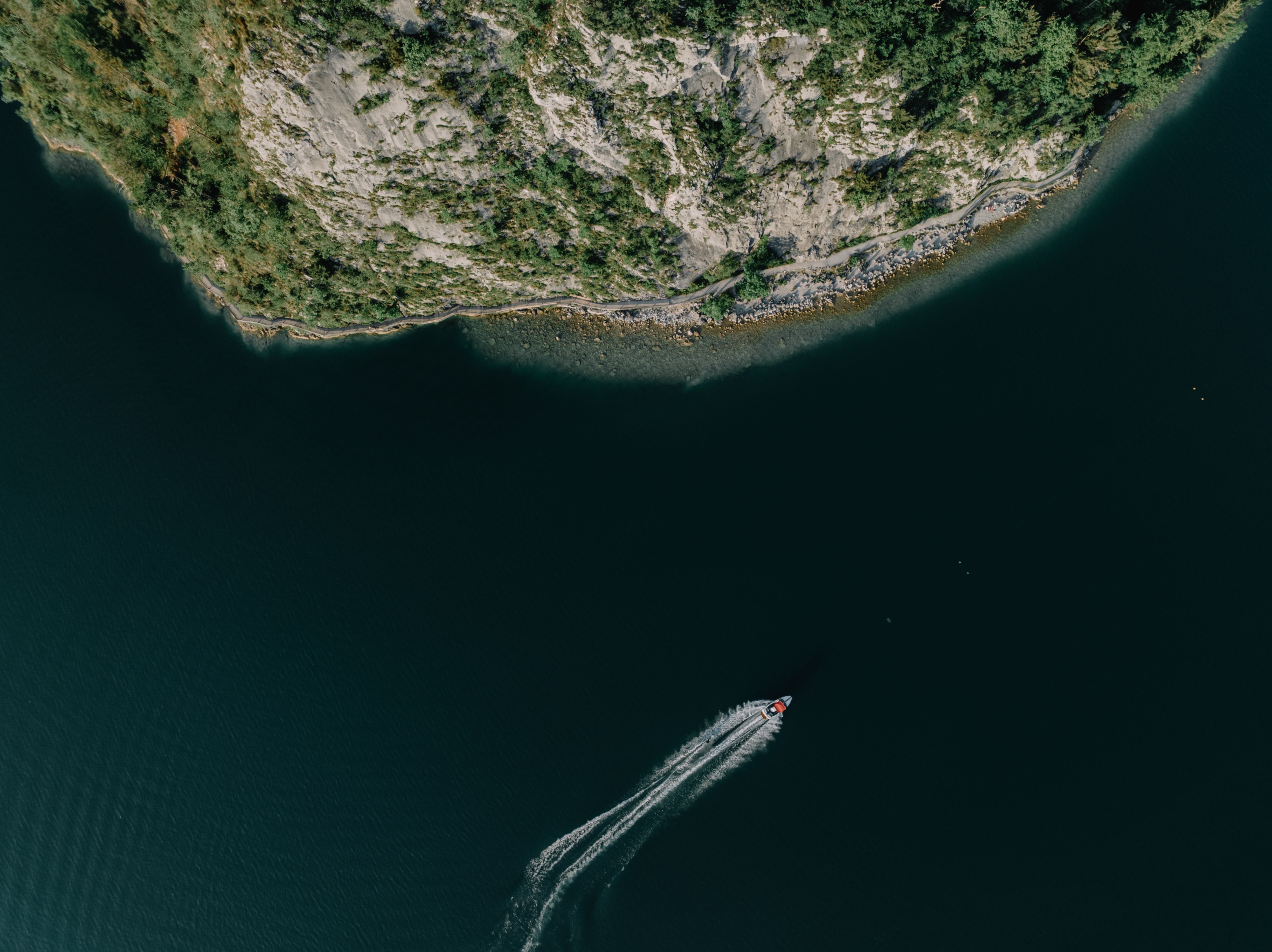 Dramatic aerial view of a motorboat on the clear waters of Lake Fuschl, near Salzburg, Austria.