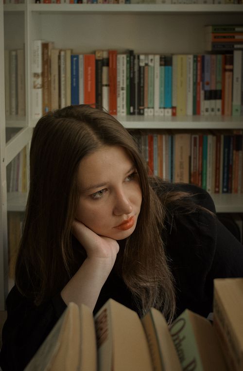 Free A young woman contemplating among books in a cozy library setting. Stock Photo