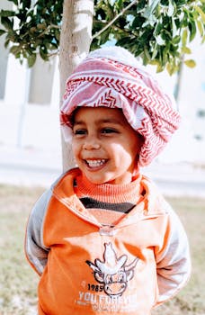 阳光明媚的一天，孩子穿着色彩缤纷的衣服，戴着凯菲耶微笑