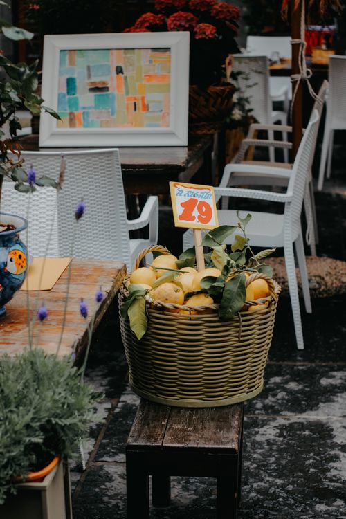 Free Wicker basket filled with lemons on a bench in an outdoor market setting. Stock Photo