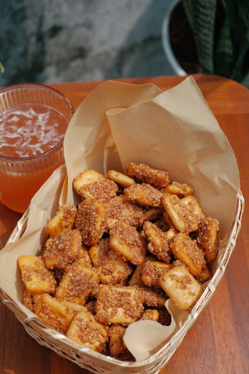 Free Close-up of crunchy snacks in a basket on a wooden table with a glass of drink. Stock Photo