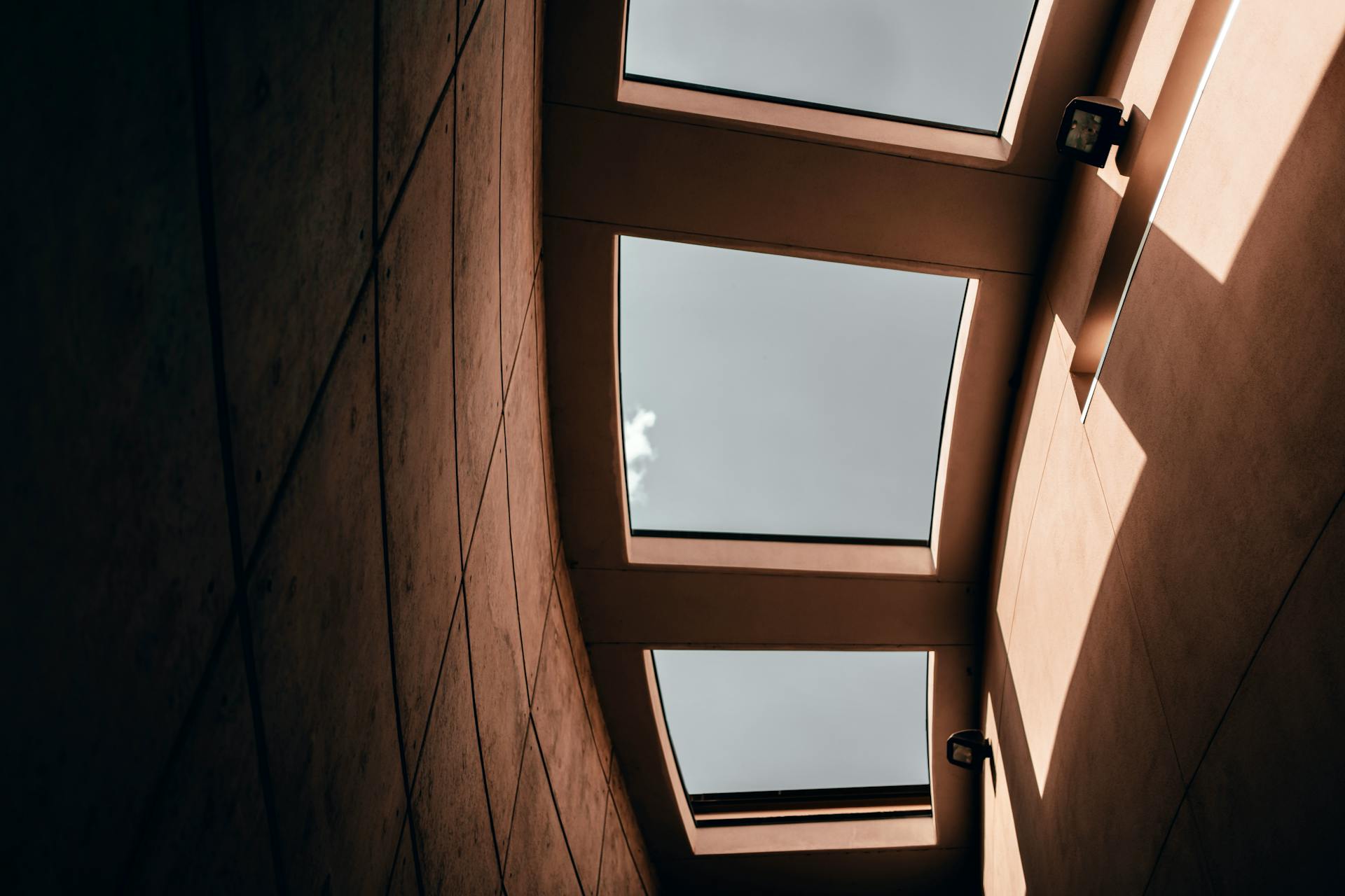 Dynamic view of a modern interior ceiling with glass panels casting distinctive shadows.