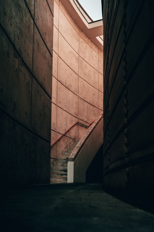 Free Vertical shot of an urban concrete staircase between towering walls, capturing modern architectural design. Stock Photo