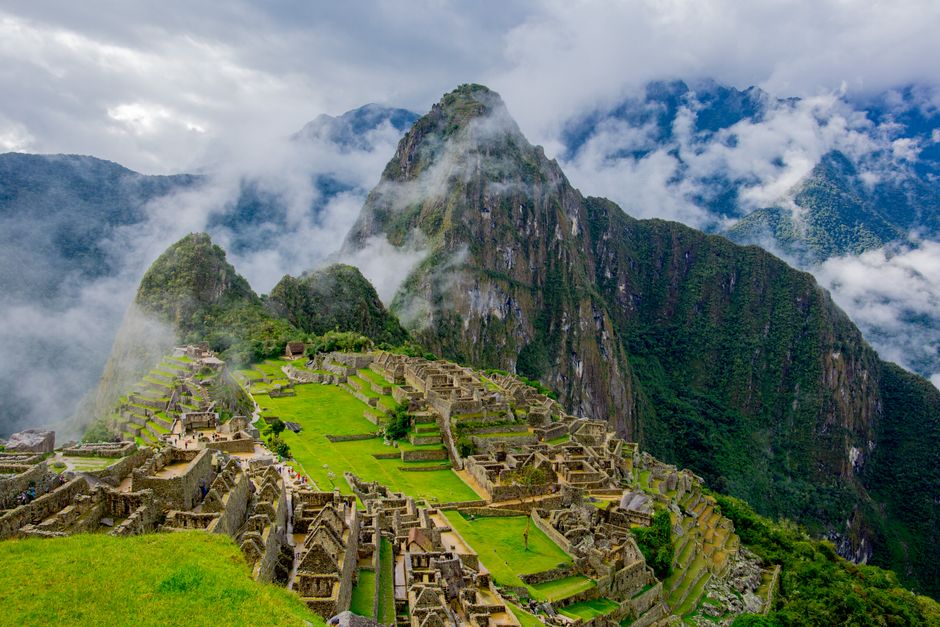 Stunning aerial view of Machu Picchu ruins surrounded by lush mountains and mist.