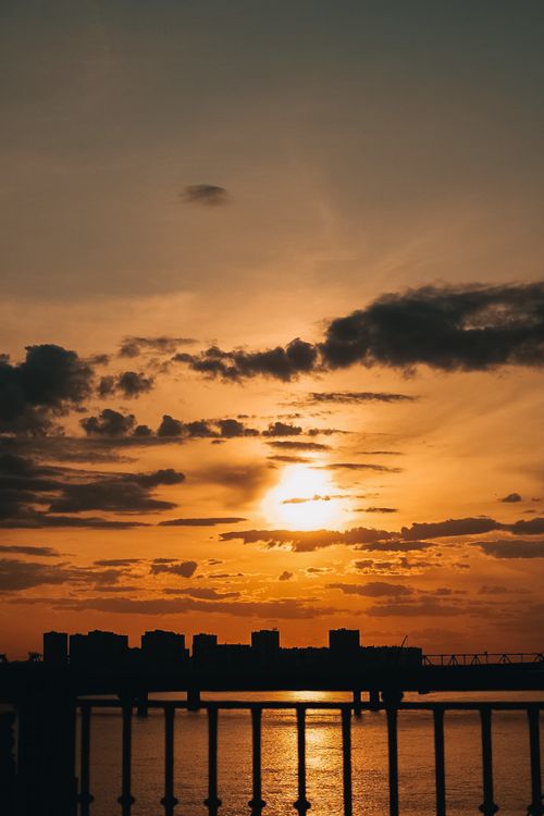 Free Dramatic sunset over New York City skyline with silhouetted buildings and railings. Stock Photo