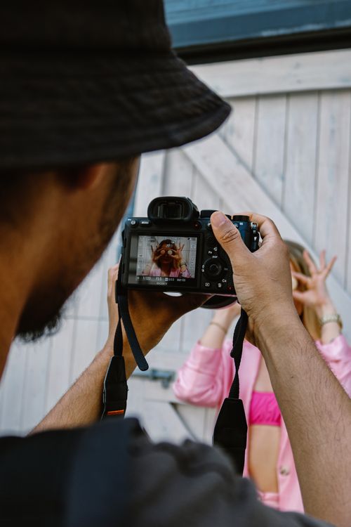 Free Close-up of a photographer capturing a woman's playful pose outdoors in a photo session. Stock Photo