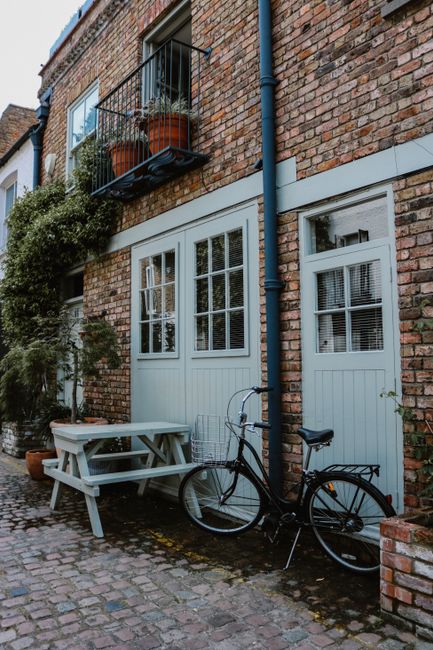 Charming scene of a bicycle beside a brick building with a picnic table.