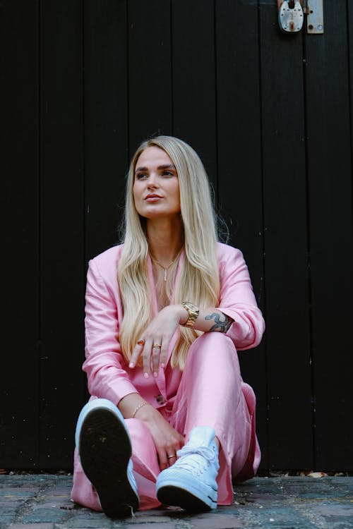 Blonde Woman in Pink Clothes Sitting on Pavement