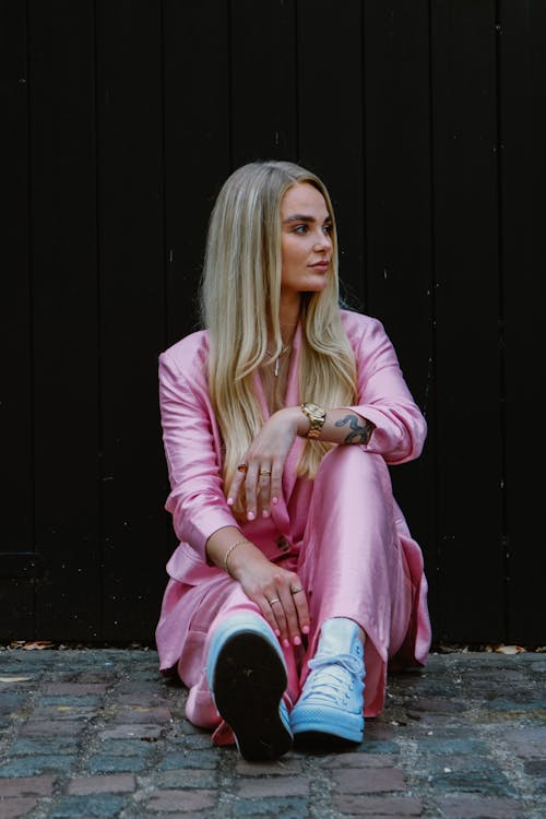 Woman in Pink Clothes Sitting and Posing on Pavement