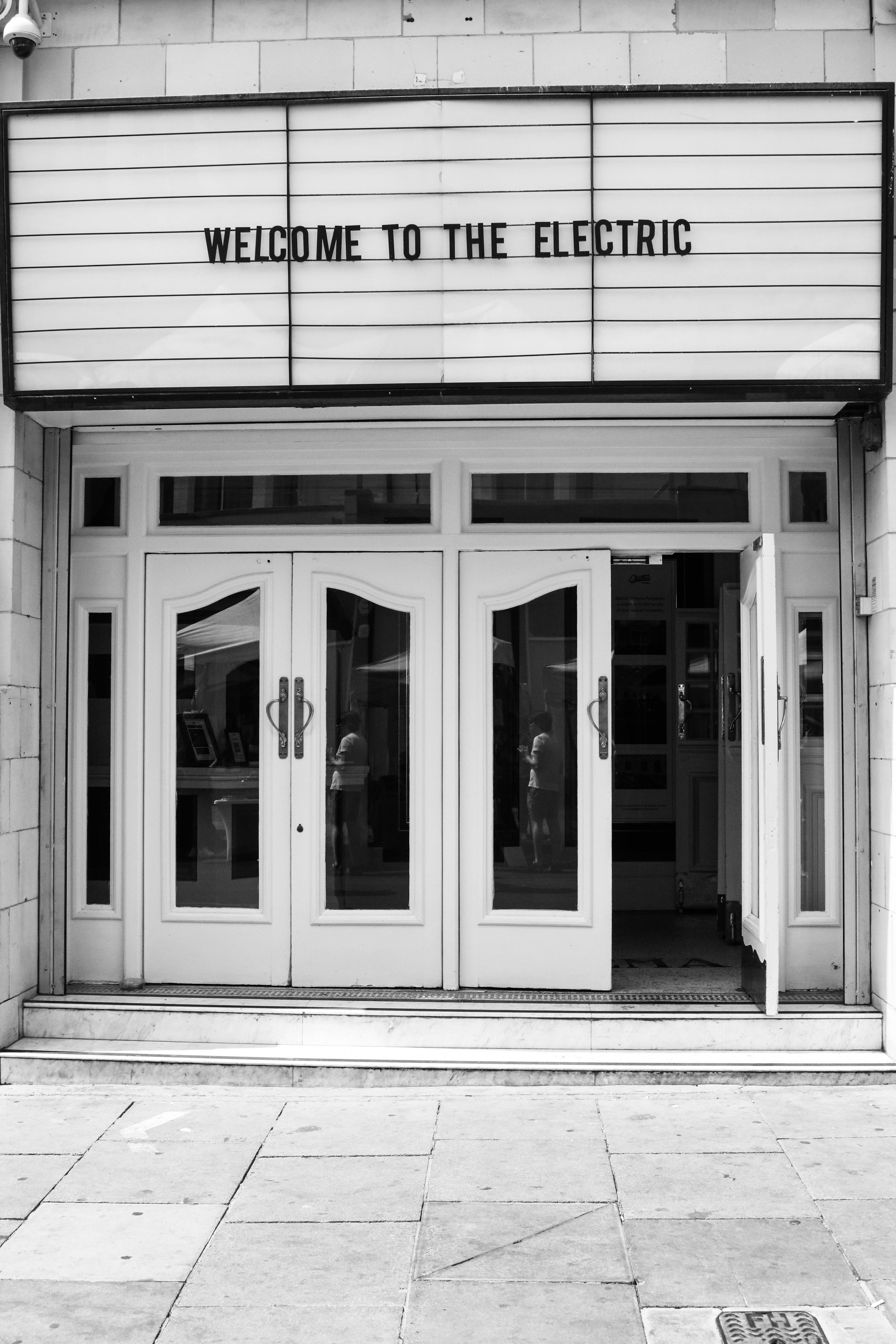 Free A monochrome image of an urban theater entrance with open doors and welcome sign. Stock Photo