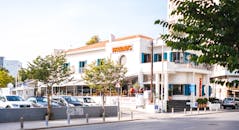 阳光明媚的街道上，餐厅、汽车和行人点缀着迷人的城市场景