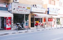 街景中，多样化的店面、一辆摩托车以及白天坐在外面的人们一览无余