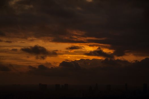 A breathtaking view of a sunset with dramatic clouds over a city skyline. Perfect for themes of tranquility and beauty.