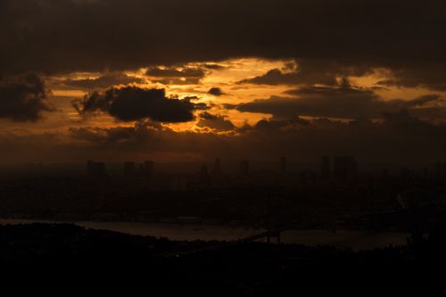 Free Silhouette of a cityscape under a dramatic sunset sky with dark clouds. Stock Photo