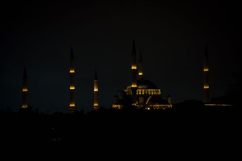 Free Silhouette of a beautifully lit mosque against a dark night sky, showcasing its minarets and architectural elegance. Stock Photo