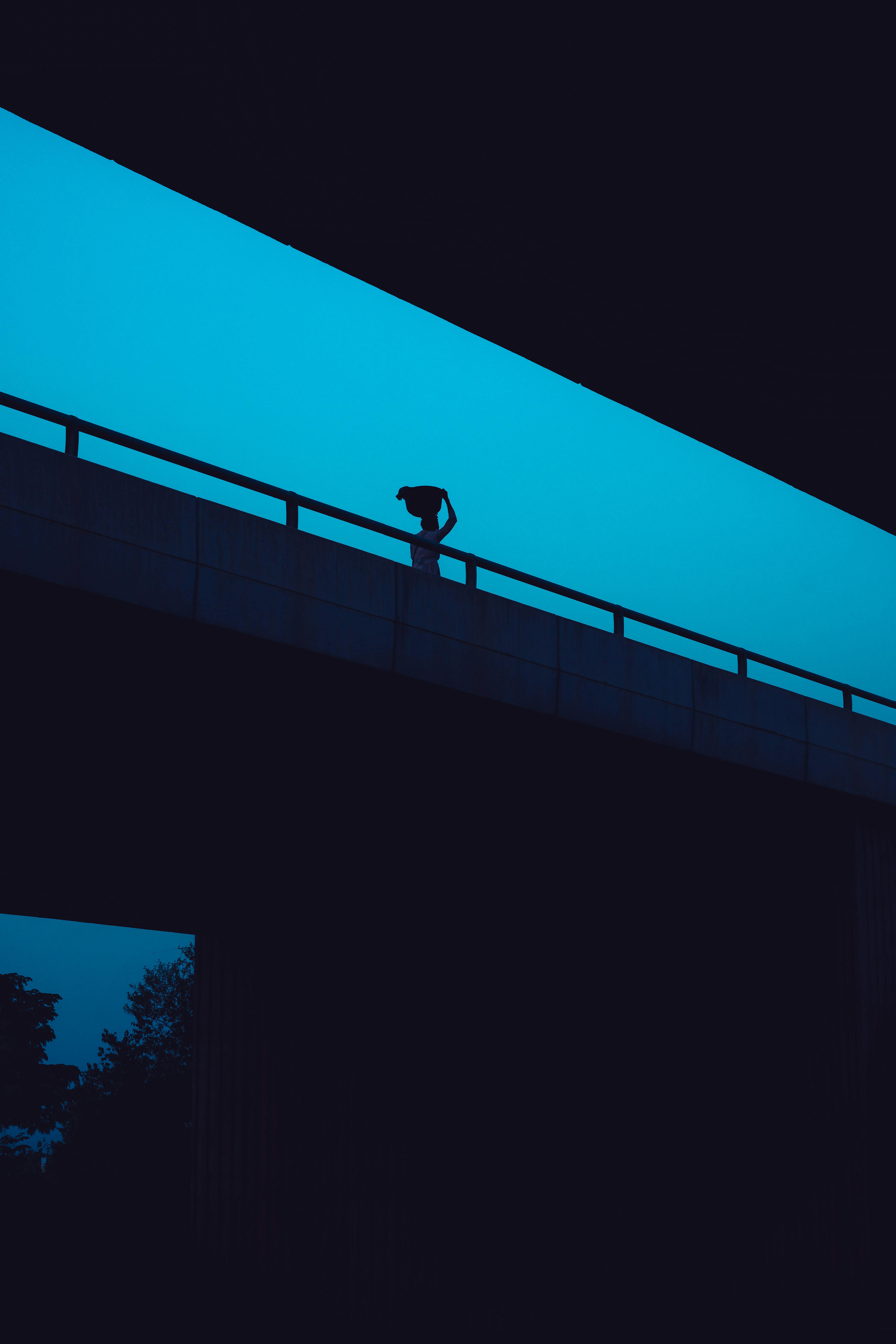 A mysterious silhouette stands on a bridge during twilight in Abuja, Nigeria.