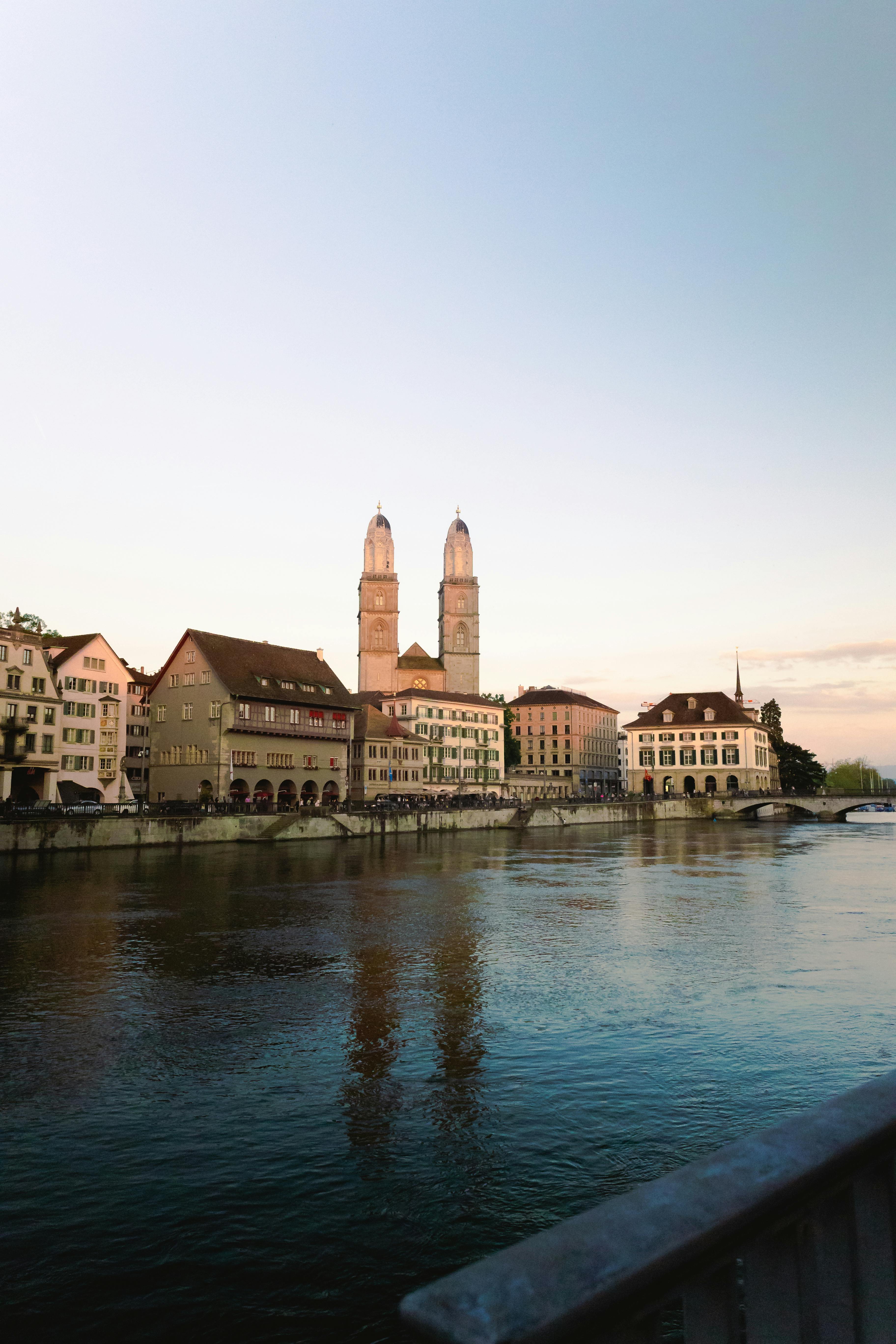 Beautiful sunset view of Grossmünster Church by the Limmat River in Zurich, Switzerland.