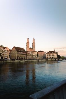 Beautiful sunset view of Grossmünster Church by the Limmat River in Zurich, Switzerland.