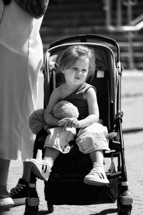 Free Adorable black and white portrait of a child sitting in a stroller, capturing a moment of childhood innocence. Stock Photo