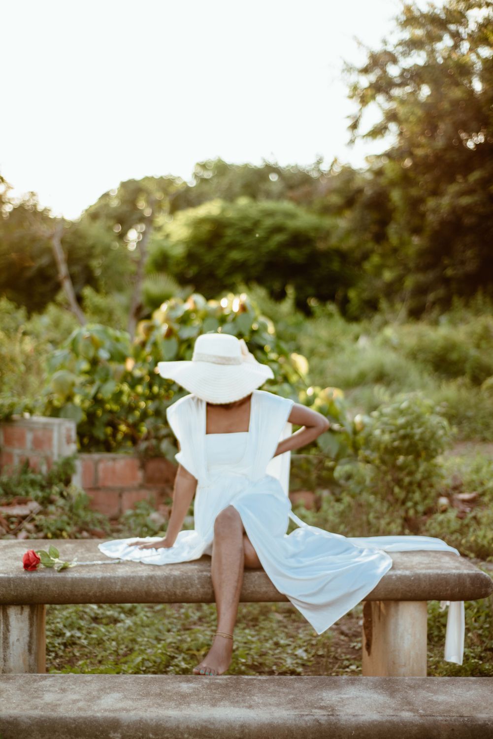 A woman in a white dress and hat sitting on a bench · Free Stock Photo