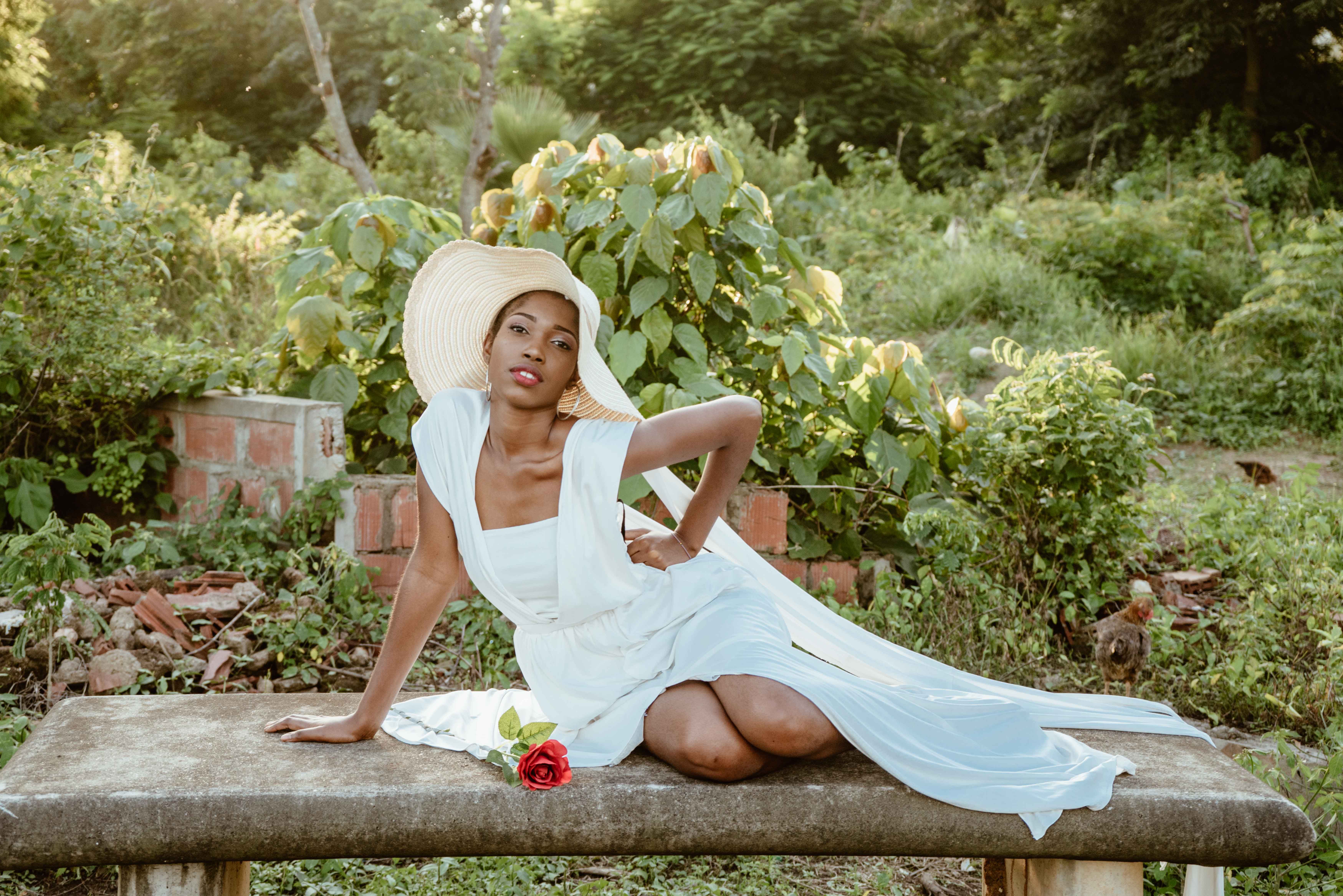 A woman in a white dress and hat sitting on a bench · Free Stock Photo