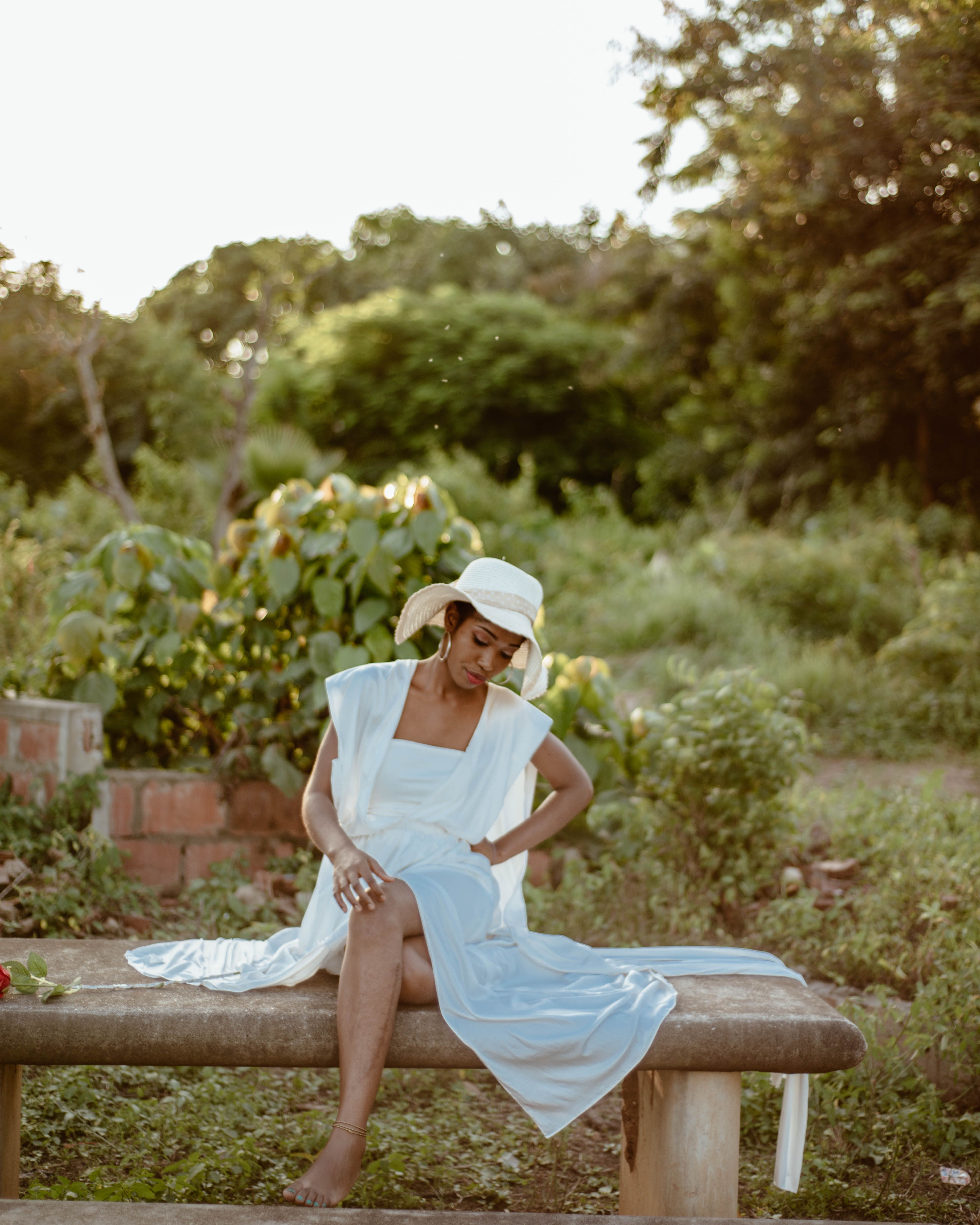 A woman in a white dress sitting on a bench · Free Stock Photo