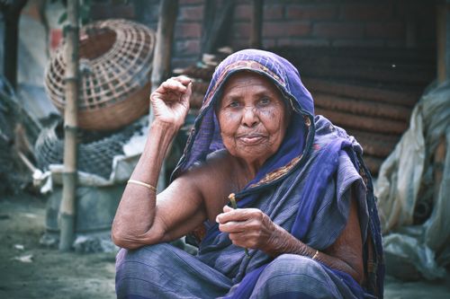 Free Portrait of an elderly woman in traditional attire sitting outdoors, showcasing cultural heritage. Stock Photo