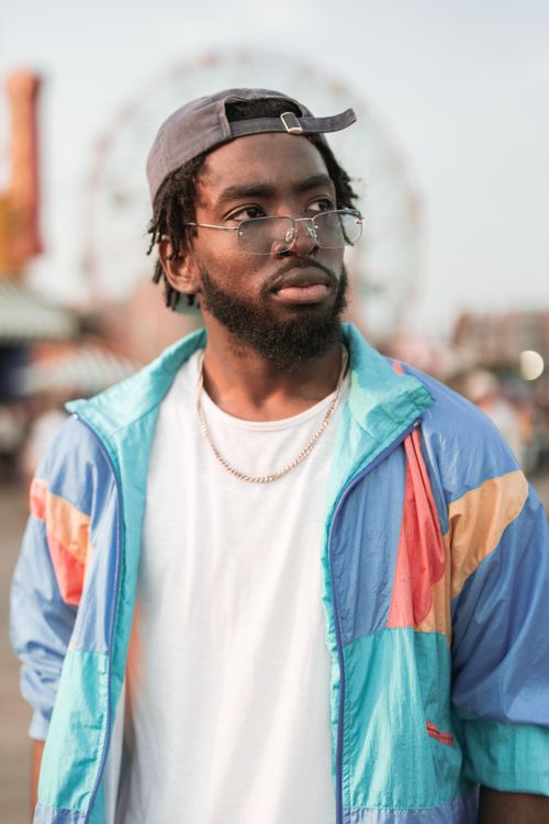 Free Fashionable man with beard and eyeglasses in a colorful jacket, outdoors. Stock Photo