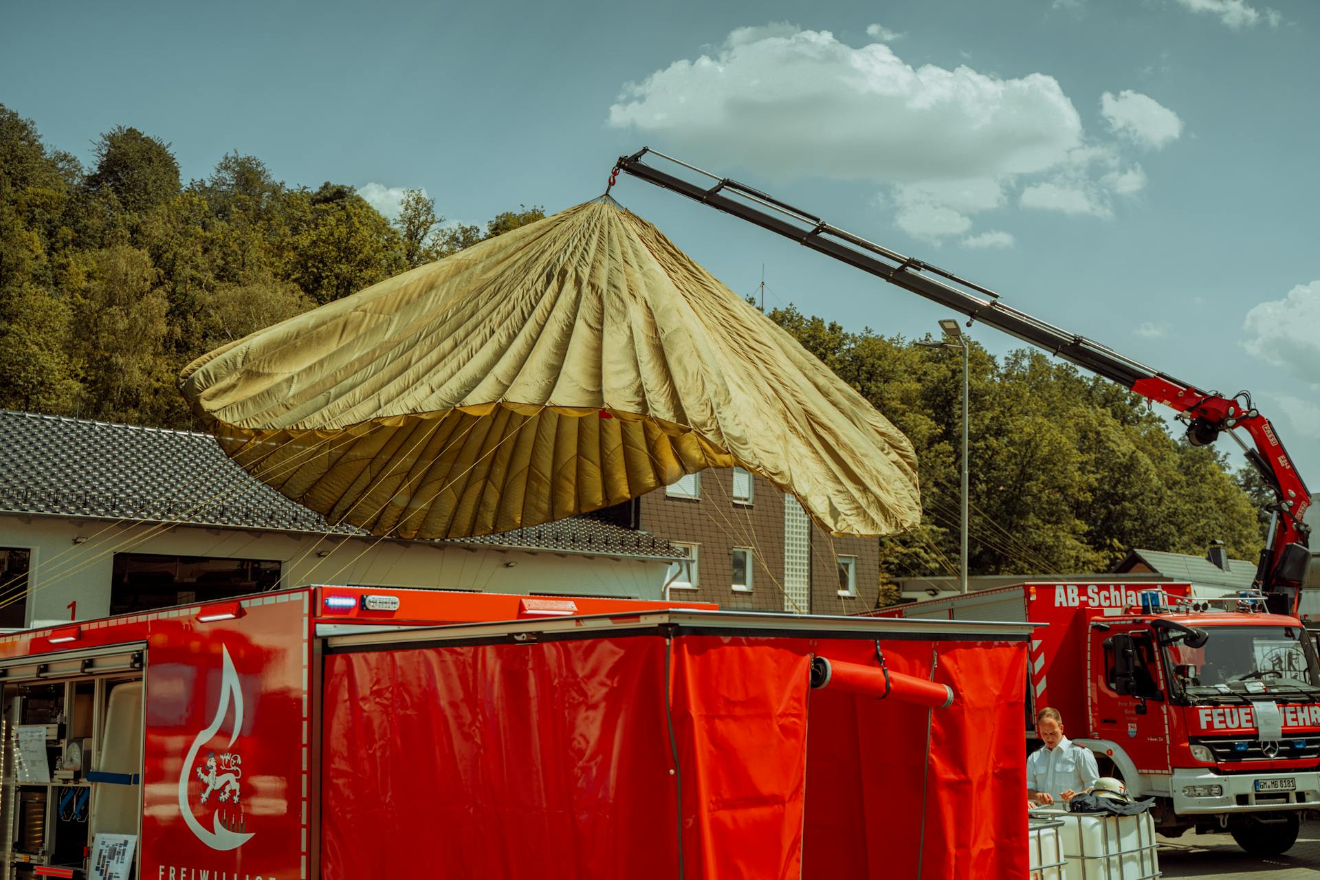 Fire brigade crane lifting parachute-like equipment in German town outdoors.