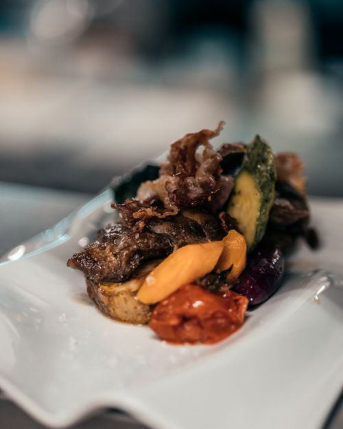 Free A close-up of a gourmet meat and vegetable dish on a white plate, showcasing vibrant colors and textures. Stock Photo