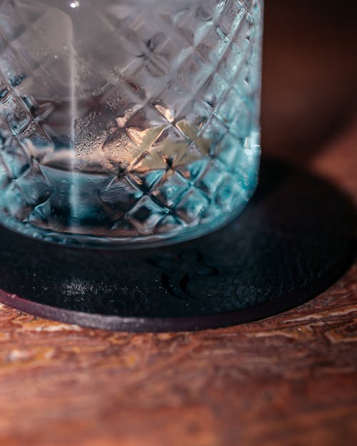 Crystal Glass of Drink on a Coaster Lying on a Wooden Table