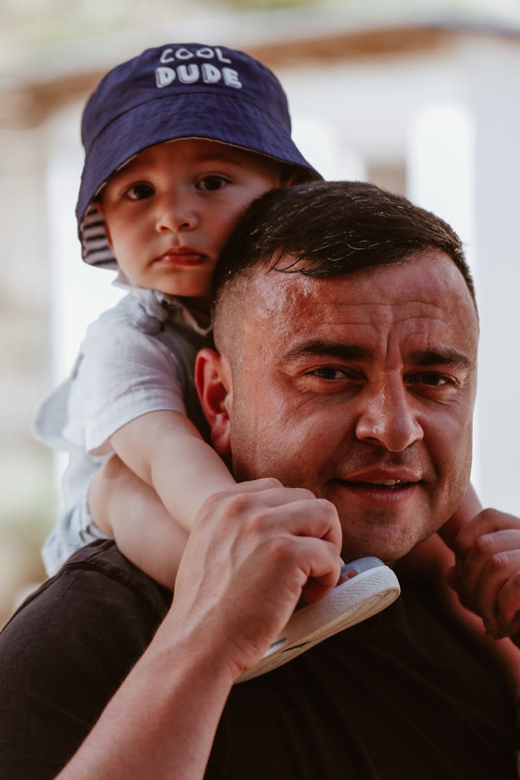 Loving Father Carrying His Toddler Son On His Shoulders