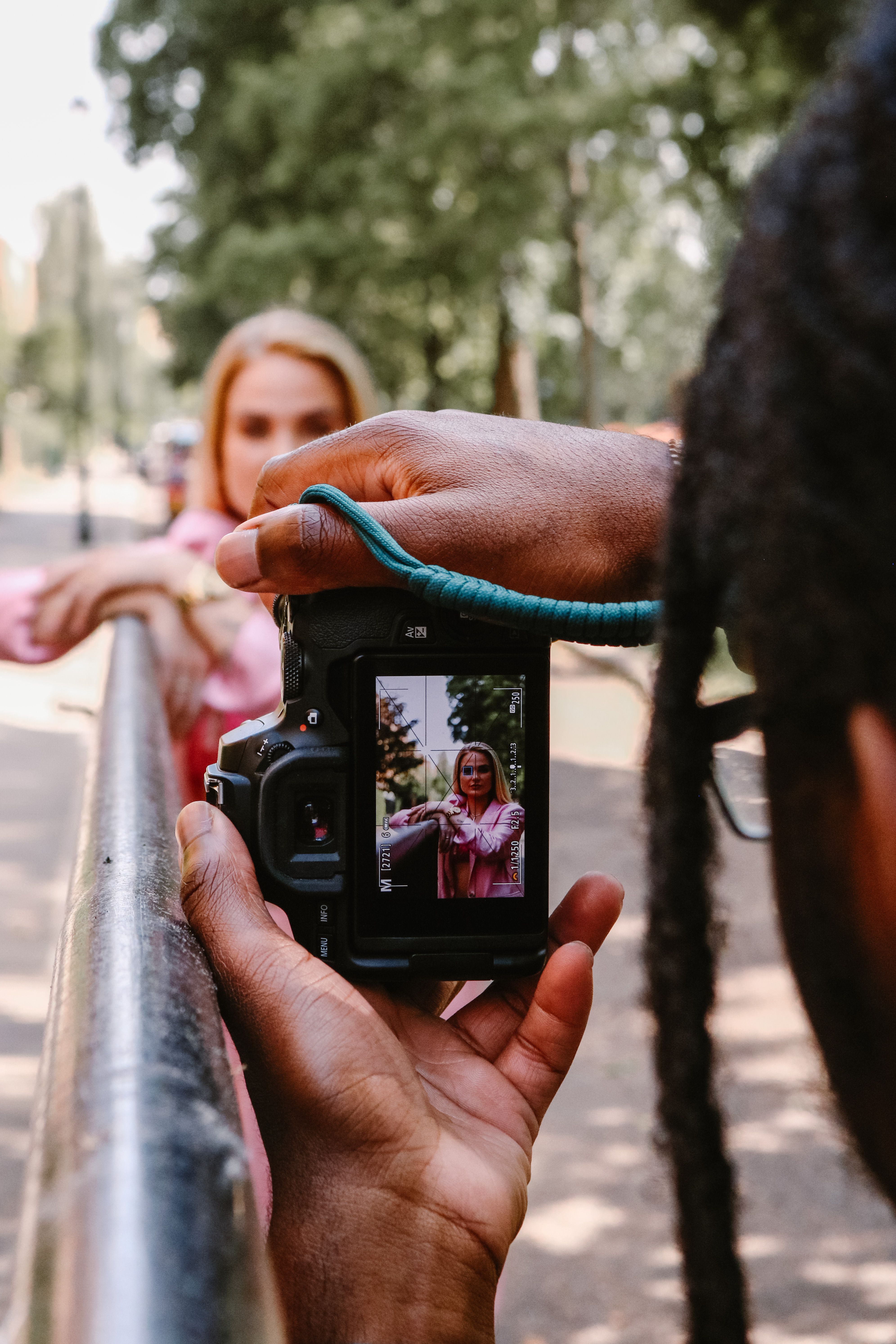 A photographer captures a woman in a vibrant pink outfit, emphasizing urban style.