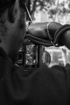 Professional photographer captures a model in an urban setting, focusing through a camera viewfinder.