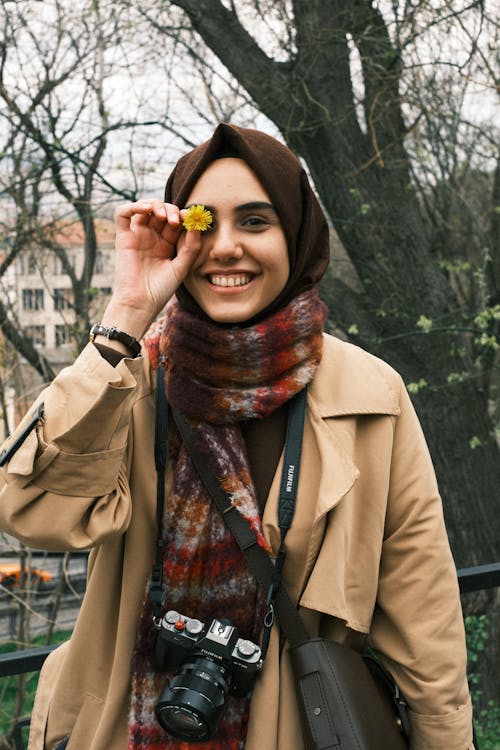 Smiling Woman in Hijab Holding Flower over Face