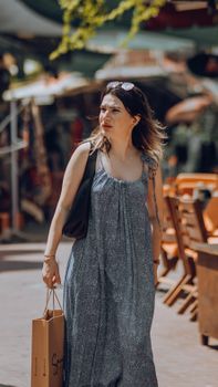 Stylish woman in a flowing dress enjoys summer shopping with her sunglasses on.