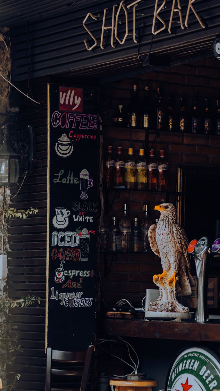 Small chalkboard menu sign mounted beside a coffee and tea bar with handwritten drink options