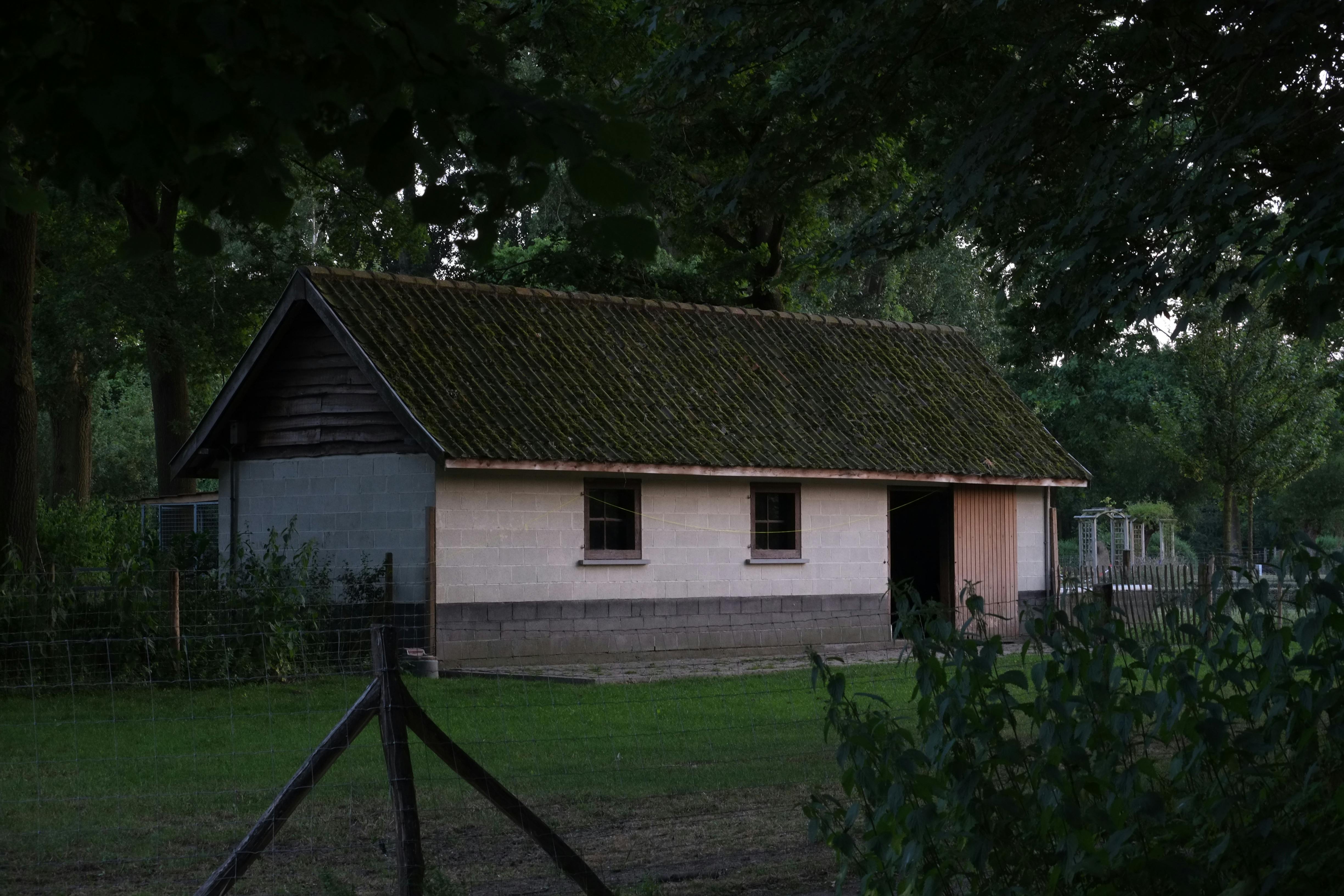 Charming old barn in rural Ghent, Belgium. Serene country scene with lush greenery and rustic architecture.