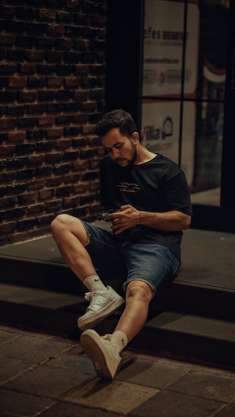 Man Sitting On Step By Glass Door