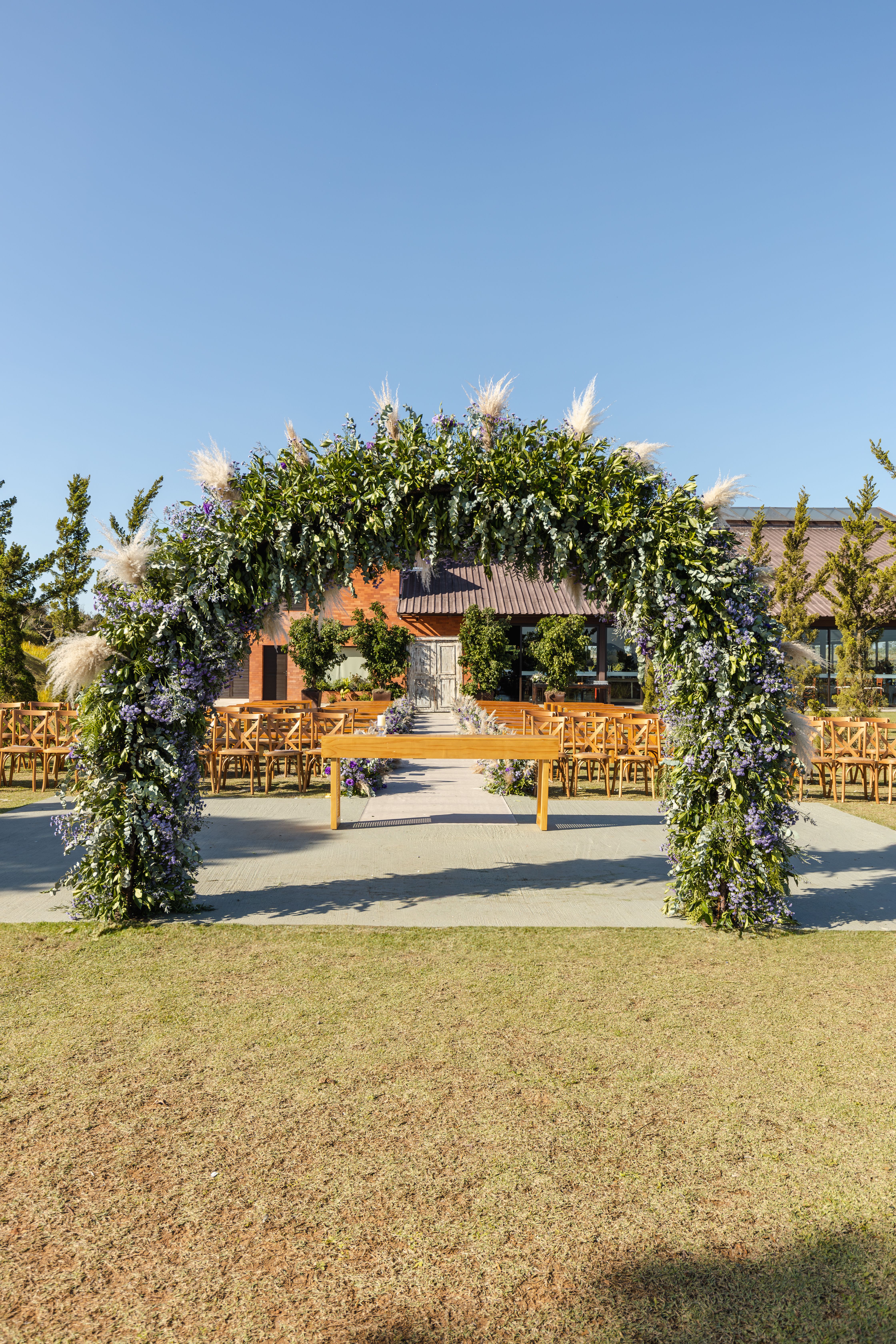 Stunning outdoor wedding venue featuring a floral arch with wooden chairs setup.