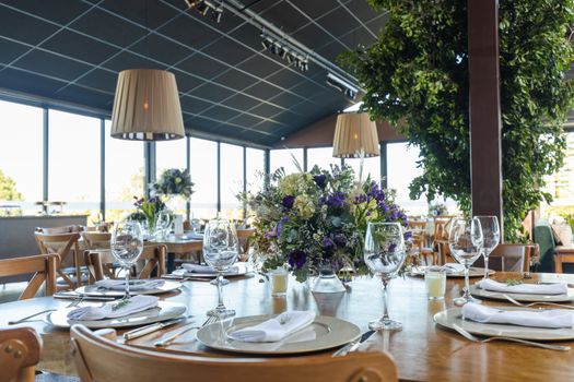A beautifully set wedding reception table with floral centerpieces and glassware in a modern venue.