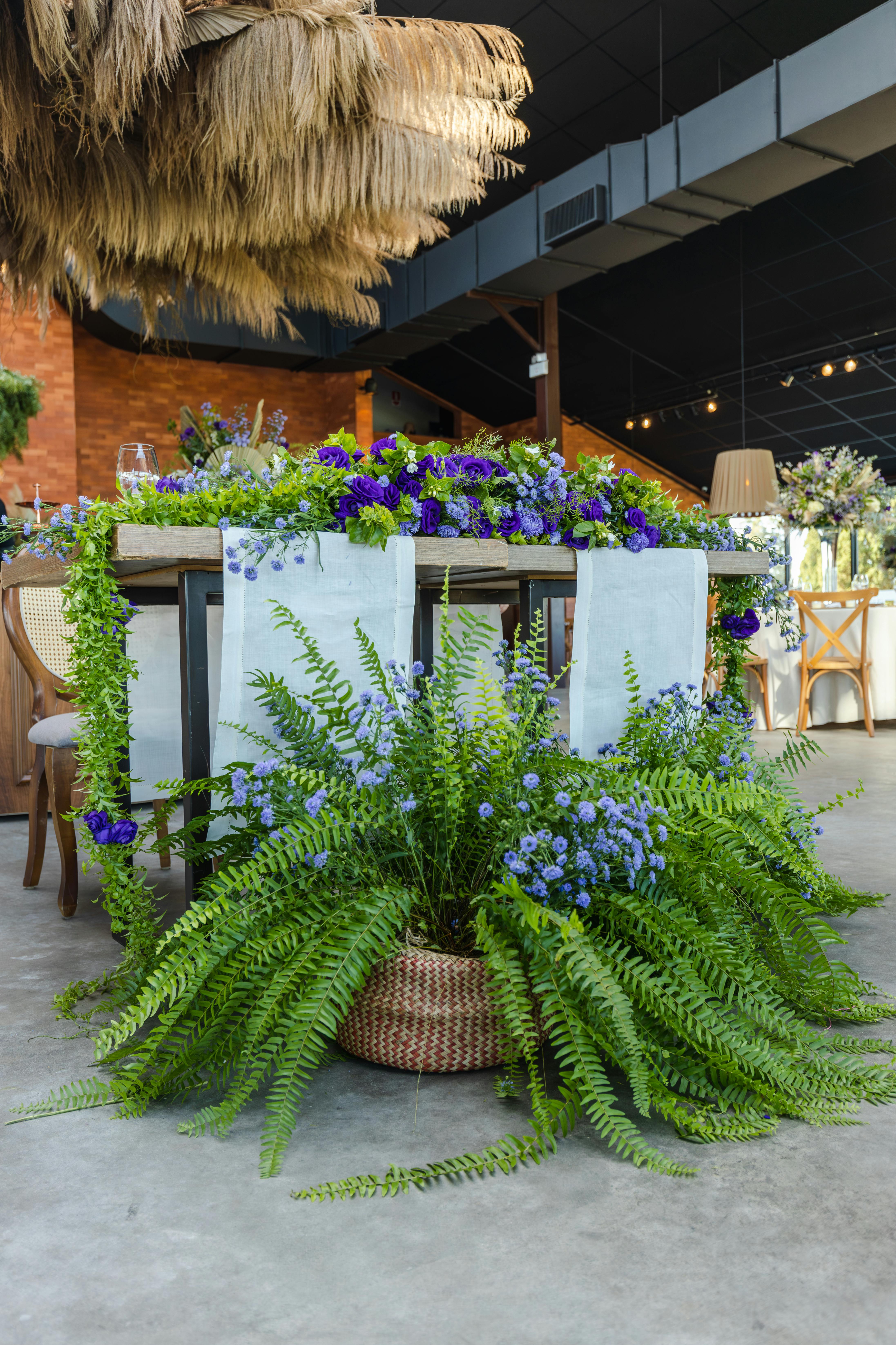 Beautifully decorated indoor venue with ferns and blue flowers, perfect for weddings or receptions.
