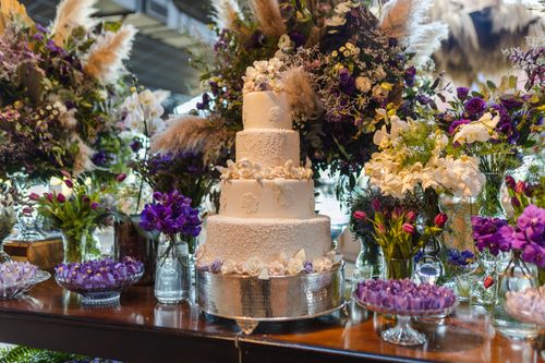 Free Luxurious white wedding cake surrounded by vibrant floral arrangements, perfect for upscale celebrations. Stock Photo