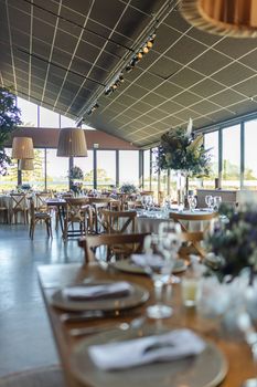 Chic wedding reception hall featuring upscale decor, natural lighting, and elegantly set tables.