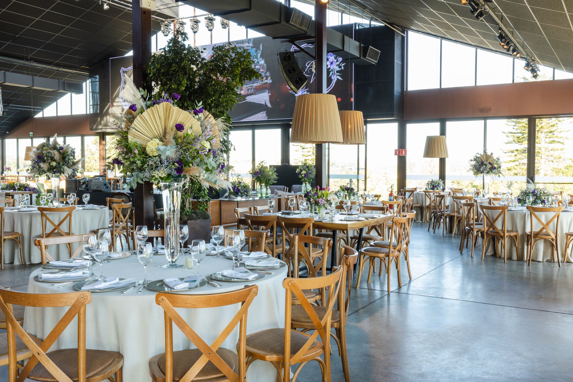 A beautifully decorated wedding reception hall with floral arrangements, elegant lighting, and arranged tables.