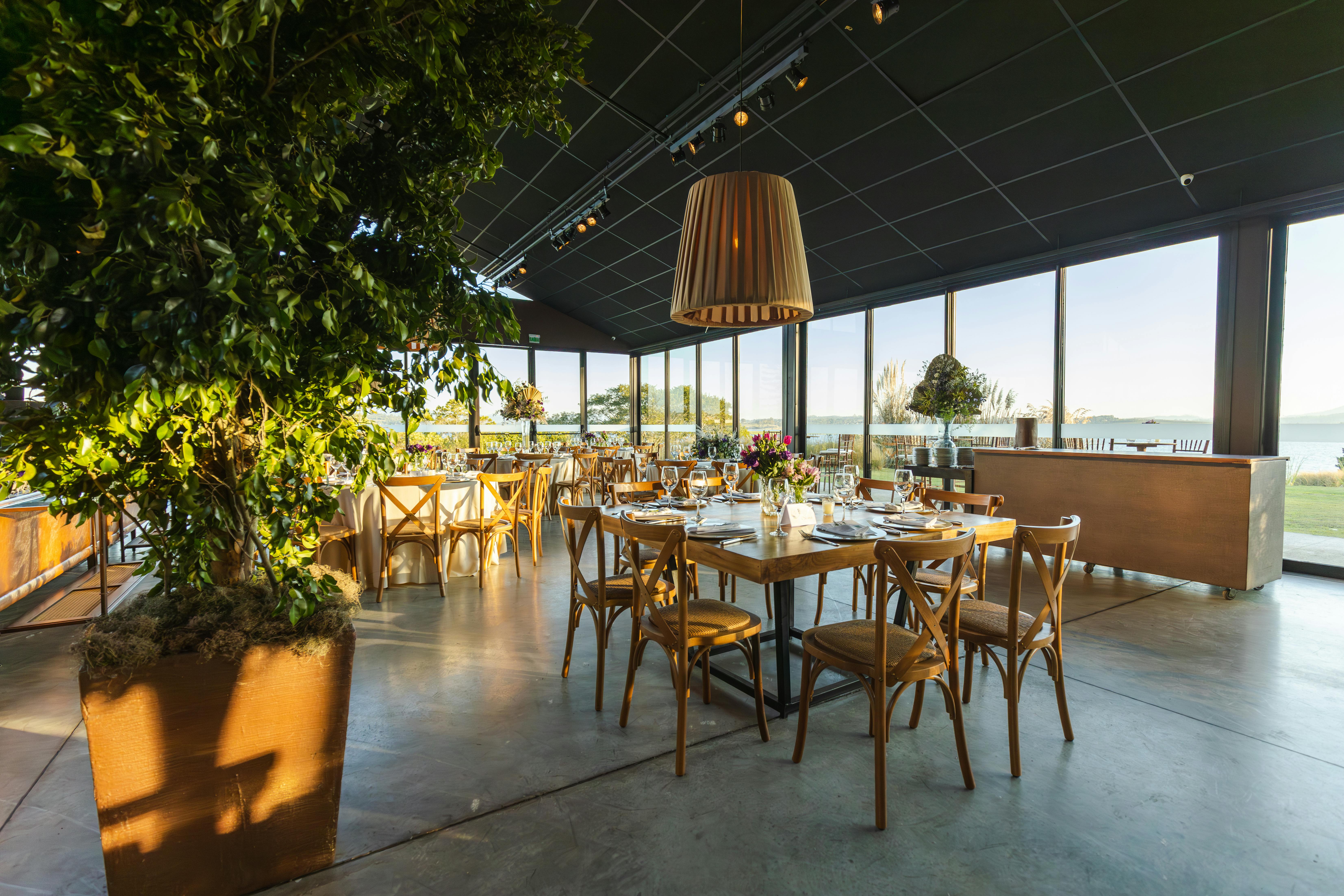 Spacious banquet hall with elegant decor, natural lighting, and a scenic outdoor view.
